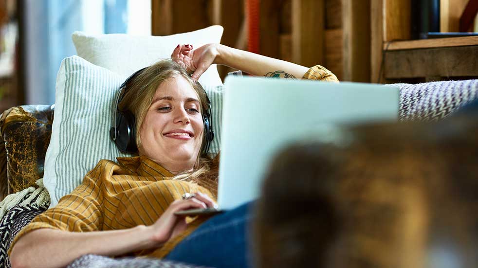 Loneliness at Christmas woman lying on sofa laughing at laptop